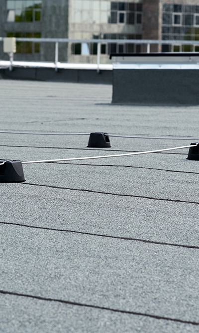 flat roofing surface with black mounts and white cable demonstrating 11 roofing components in view