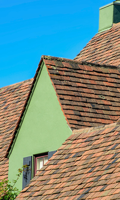 roof design with green painted gable and slate tiles under blue sky