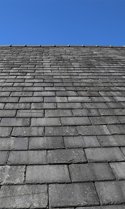 flat gray slate roof against clear blue sky showcasing 12 evenly aligned tiles