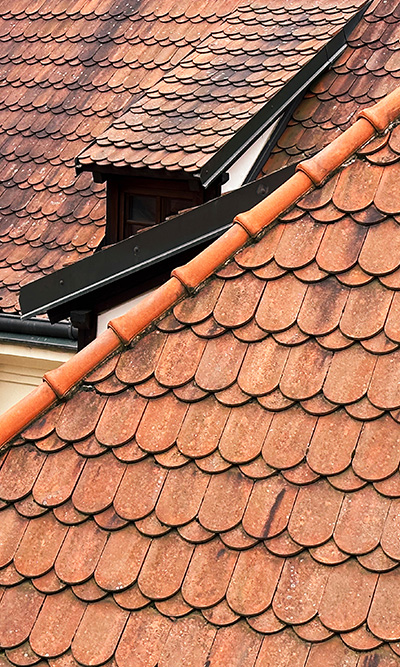terracotta roof tiles in a residential area showcasing six distinct layers with an architectural dormer in the background